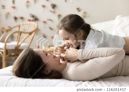 Caring mom lying on bed with cute little daughter Caring mom lying on bed with cute little daughter 116281437