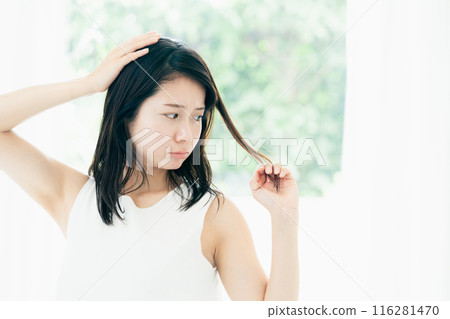 A young woman who is concerned about damaged hair A young woman who is concerned about damaged hair 116281470
