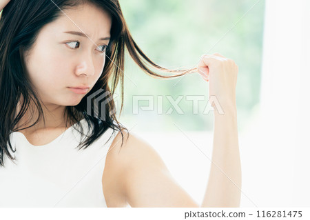 A young woman who is concerned about damaged hair A young woman who is concerned about damaged hair 116281475