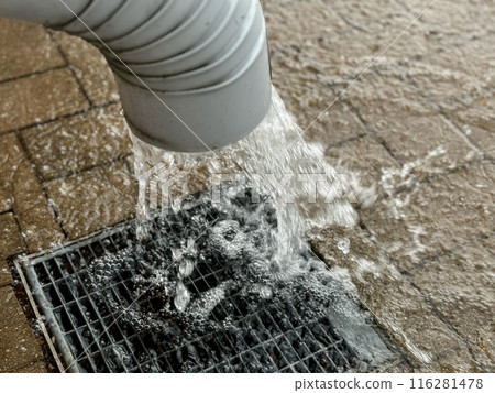 Gutter or drain pipe by the wall of the building, rapid flow of water after heavy rain 116281478