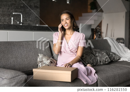 Happy young consumer woman speaking on mobile phone at home 116281550