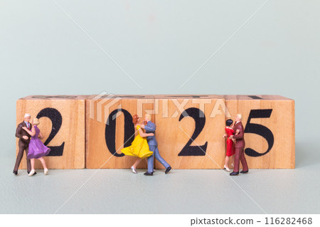 A group of miniature dancers dance on wooden blocks arranged to represent the year 2025. A group of miniature dancers dance on wooden blocks arranged to represent the year 2025. 116282468
