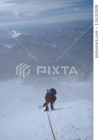 Mountaineers Ascending Steep Snow Slope on High Mountain, Roped Together Under Soft Snowfall 116282606
