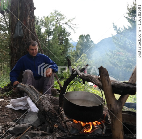 Man cooking a traditional meal over an open fire in the mountains 116282691