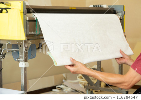 A craftsman preparing wallpaper for a house 116284547