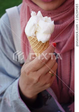 Female holds in her hand a cone with ice cream Female holds in her hand a cone with ice cream 116284565