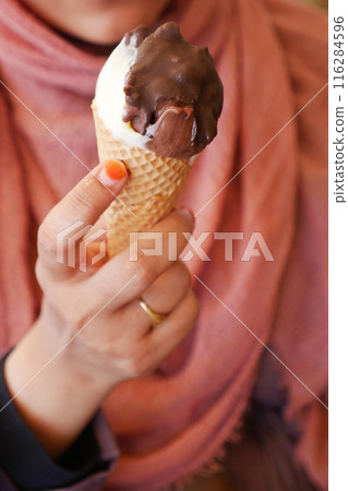 Female holds in her hand a cone with ice cream Female holds in her hand a cone with ice cream 116284596