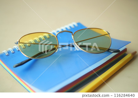 notepad, eyeglass and a pencil on wooden table  116284640