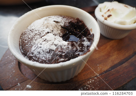 Delicious Chocolate Lava Cake with Powdered Sugar and Whipped Cream on Wooden Plate Delicious Chocolate Lava Cake with Powdered Sugar and Whipped Cream on Wooden Plate 116284703