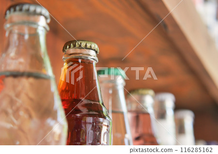 Vintage beverage bottles with colorful caps on bar shelf create a nostalgic retro drinks display Vintage beverage bottles with colorful caps on bar shelf create a nostalgic retro drinks display 116285162