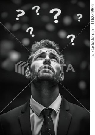 A man in a suit is looking up with a question mark on his forehead 116286906