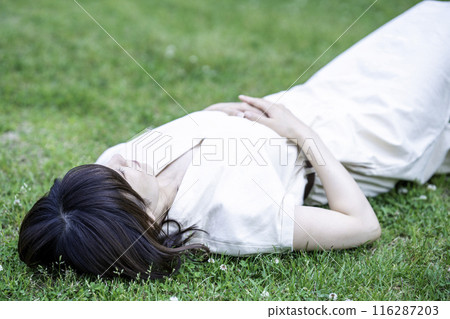 一個女人躺在新鮮的綠色草地上 116287203