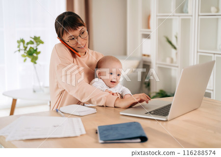 Business mom working remotely on laptop while taking care of her baby 116288574