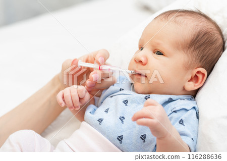 Newborn baby receiving liquid vitamin K from a dropper 116288636