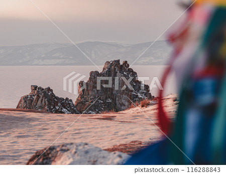 A vibrant, blurry bundle of colorful ribbons frames the view of a dramatic rock formation on Olkhon Island in Siberia. 116288843
