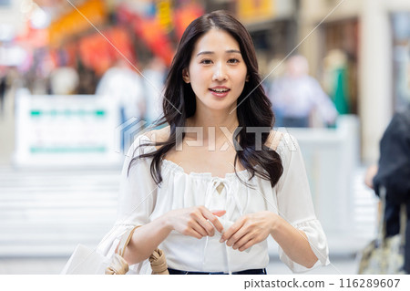 Young woman walking through a shopping street 116289607