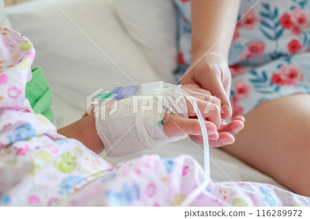 Mother holding child hand with saline IV solution in hospital 116289972