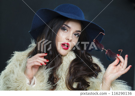 Charming fashion model woman with long dark wavy hairstyle and red lips make-up Charming fashion model woman with long dark wavy hairstyle and red lips make-up 116290136