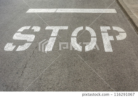 On the asphalt roadway marked the road marking "STOP" On the asphalt roadway marked the road marking "STOP" 116291067