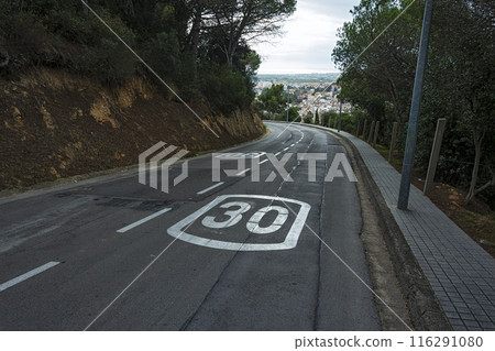 Narrow road with left turn and speed limit. A narrow mountain road with a slope with limited speed 116291080