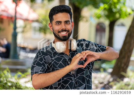 Happy Indian young man makes symbol of love showing heart sign to camera romantic positive feelings Happy Indian young man makes symbol of love showing heart sign to camera romantic positive feelings 116291659