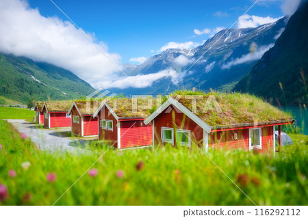 Traditional Scandinavian houses with moss on the roof. Beautiful mountain lake in Norway. 116292112