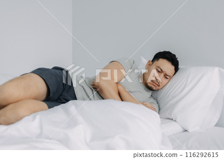Serious and depressed man overthinking the problems lying on the bed. Serious and depressed man overthinking the problems lying on the bed. 116292615