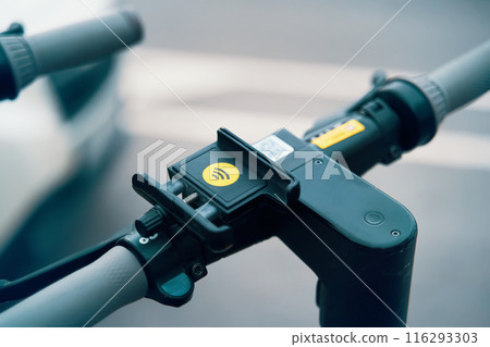 A closeup of a phone holder mounted on a scooters handlebar, showcasing a practical and convenient bicycle part. This useful tool is perfect for securely holding your phone while on the go 116293303