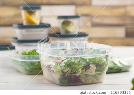 Chopped salad, vegetables and herbs in a plastic container. Storing food for freezing 116293335