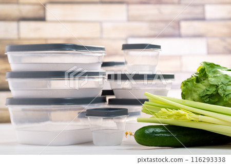 A stack of plastic containers and raw vegetables on the table. Storage for vegetables and fruits in plastic containers A stack of plastic containers and raw vegetables on the table. Storage for vegetables and fruits in plastic containers 116293338