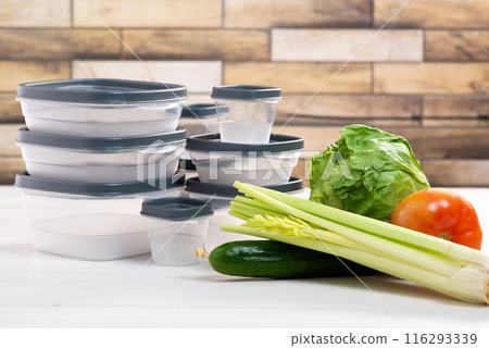 A stack of plastic containers and raw vegetables on the table. Storage for vegetables and fruits in plastic containers 116293339