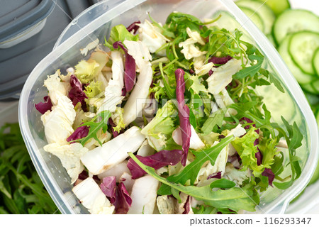 Chopped lettuce and herbs in a plastic container 116293347