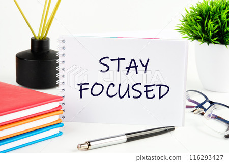 STAY FOCUSED text in a notebook on a light background in a composition with business accessories STAY FOCUSED text in a notebook on a light background in a composition with business accessories 116293427