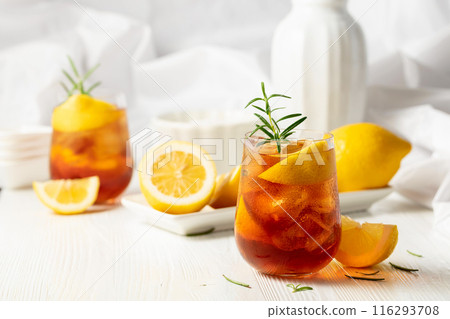 Iced tea or alcoholic cocktail with ice, rosemary and lemon slices on the white table. Iced tea or alcoholic cocktail with ice, rosemary and lemon slices on the white table. 116293708