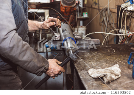 Mechanic repairing spare parts from a tractor. Mechanic repairing spare parts from a tractor. 116293802