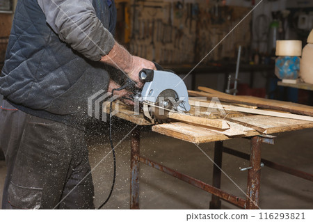 Close-up of a carpenter working circular saw. The carpenter saws wooden blocks and wood slates 116293821