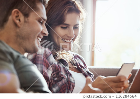 App, phone and smile with couple on sofa in living room of home together for communication or social media. Break, love or relax with happy man and woman in apartment for browsing or networking 116294564