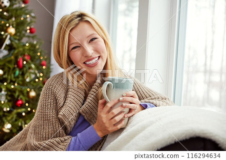 Christmas, happy woman and coffee on home sofa with smile while thinking of memory. Portrait of lady with hot chocolate or tea cup to relax for festive holiday, season or winter vacation celebration 116294634