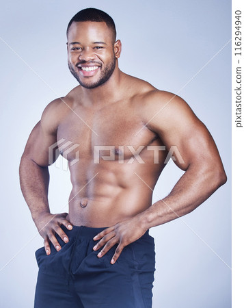 Black man, portrait and topless in studio with fitness for healthy body, happy and muscle power with confidence. Bodybuilder, athlete and smile with wellness and arm strength on blue background 116294940