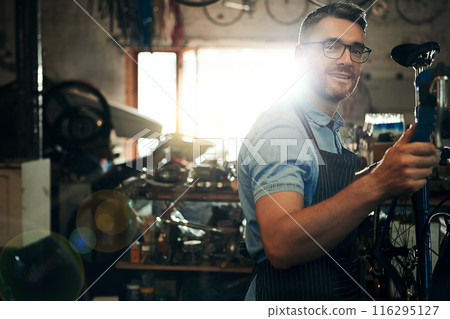 Happy man, portrait and bicycle mechanic with inspection for fix or maintenance at repair shop. Young male person, cycling technician or engineer working on bike with tools or equipment at workshop Happy man, portrait and bicycle mechanic with inspection for fix or maintenance at repair shop. Young male person, cycling technician or engineer working on bike with tools or equipment at workshop 116295127