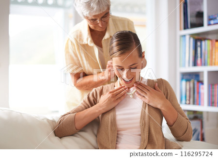 Sofa, necklace and elderly mother with woman for present, gift and surprise in living room home. Family heirloom, pearls and daughter with mom with jewellery for celebration, birthday and bonding 116295724