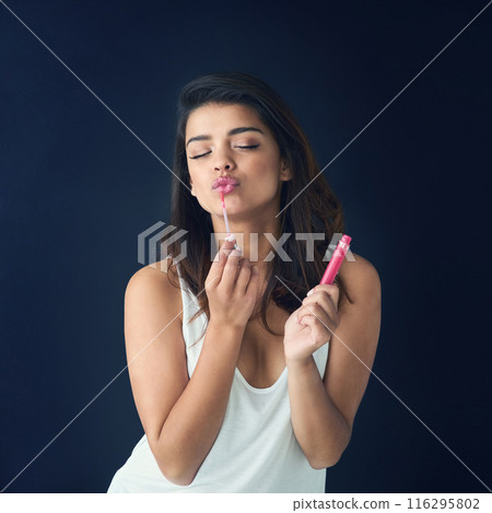 Woman, lip gloss and beauty in studio for cosmetic, product and kiss and dark background. Lipstick, cosmetology or shiny for make up and application, love and product for model person with confidence Woman, lip gloss and beauty in studio for cosmetic, product and kiss and dark background. Lipstick, cosmetology or shiny for make up and application, love and product for model person with confidence 116295802