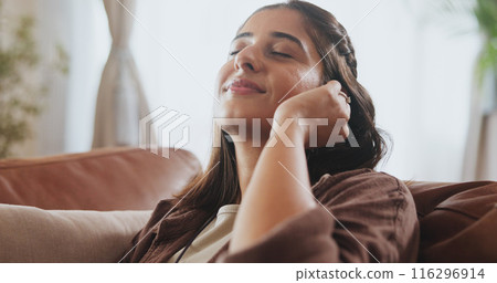 Sleeping, woman and relax on sofa house listening to music with wireless earphones, radio and podcast in living room. Smile, female person and streaming audio, connection and subscription for peace 116296914