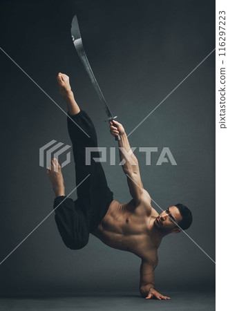 Martial arts, asian man and sword for training, fitness and self defense on dark studio background. Person, performer with skills development, talent and practice with exercise, attack and weapon 116297223