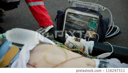 Accident, paramedic and chest with defibrillator for help, emergency and healthcare on road. First responder, medic and male victim with support, injury and life saving on tarmac with protection 116297311