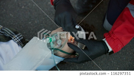 First aid, paramedic and check man with flashlight for emergency ems service, accident and oxygen mask. Hands, medical or light on unconscious patient eyes for healthcare, help or rescue in top view First aid, paramedic and check man with flashlight for emergency ems service, accident and oxygen mask. Hands, medical or light on unconscious patient eyes for healthcare, help or rescue in top view 116297351