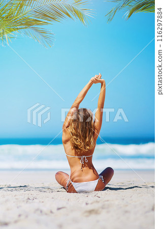 Woman, stretching and relax in bikini on beach sand for adventure, holiday or sunshine at tropical resort in Maldives. Female person, back and travel on vacation, peace or blue sky by ocean waves 116297884