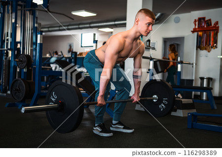 A bodybuilder performs a deadlift exercise in a gym setting A bodybuilder performs a deadlift exercise in a gym setting 116298389