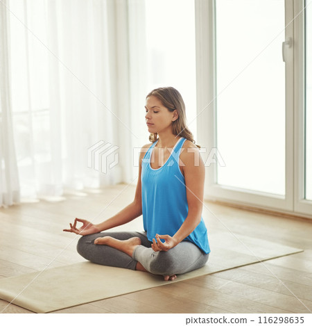 Woman, meditation and wellness with lotus for peace, calm and eyes closed for mindfulness at home. Young person on floor or yoga mat for zen and spiritual, holistic or breathing exercise to relax 116298635