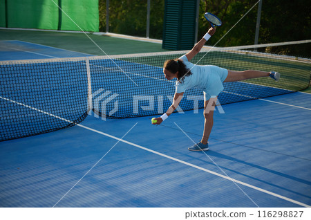 Woman playing tennis on outdoor court in action stance Woman playing tennis on outdoor court in action stance 116298827